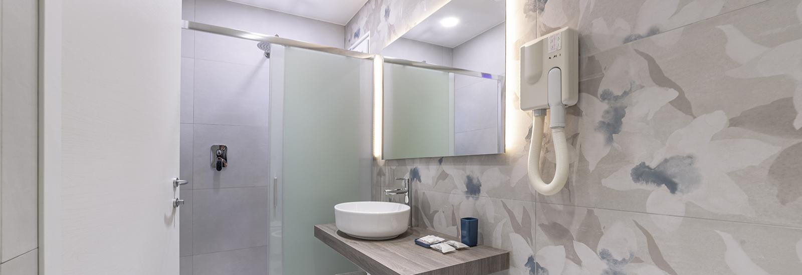 Modern bathroom with shower, sink, and illuminated mirror.