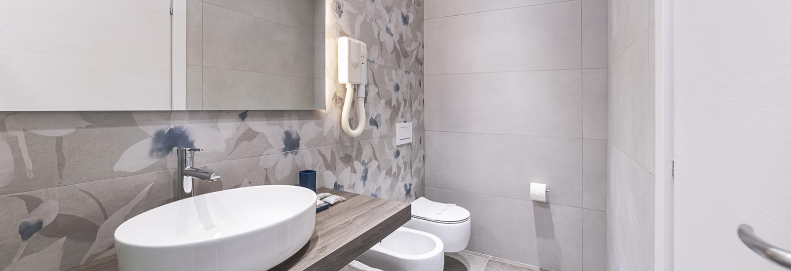 Modern bathroom with sink, bidet, and floral wallpaper.