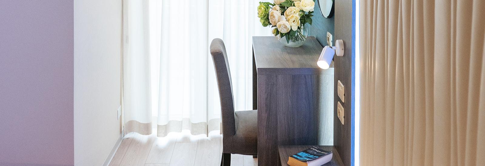 Bright room with desk, flowers, and book.